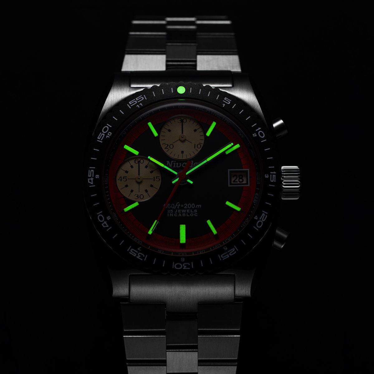 The Autochron Automatic Orange photographed in the dark, its applied markers and central hands glowing green with Super-LumiNova against the black dial and bezel