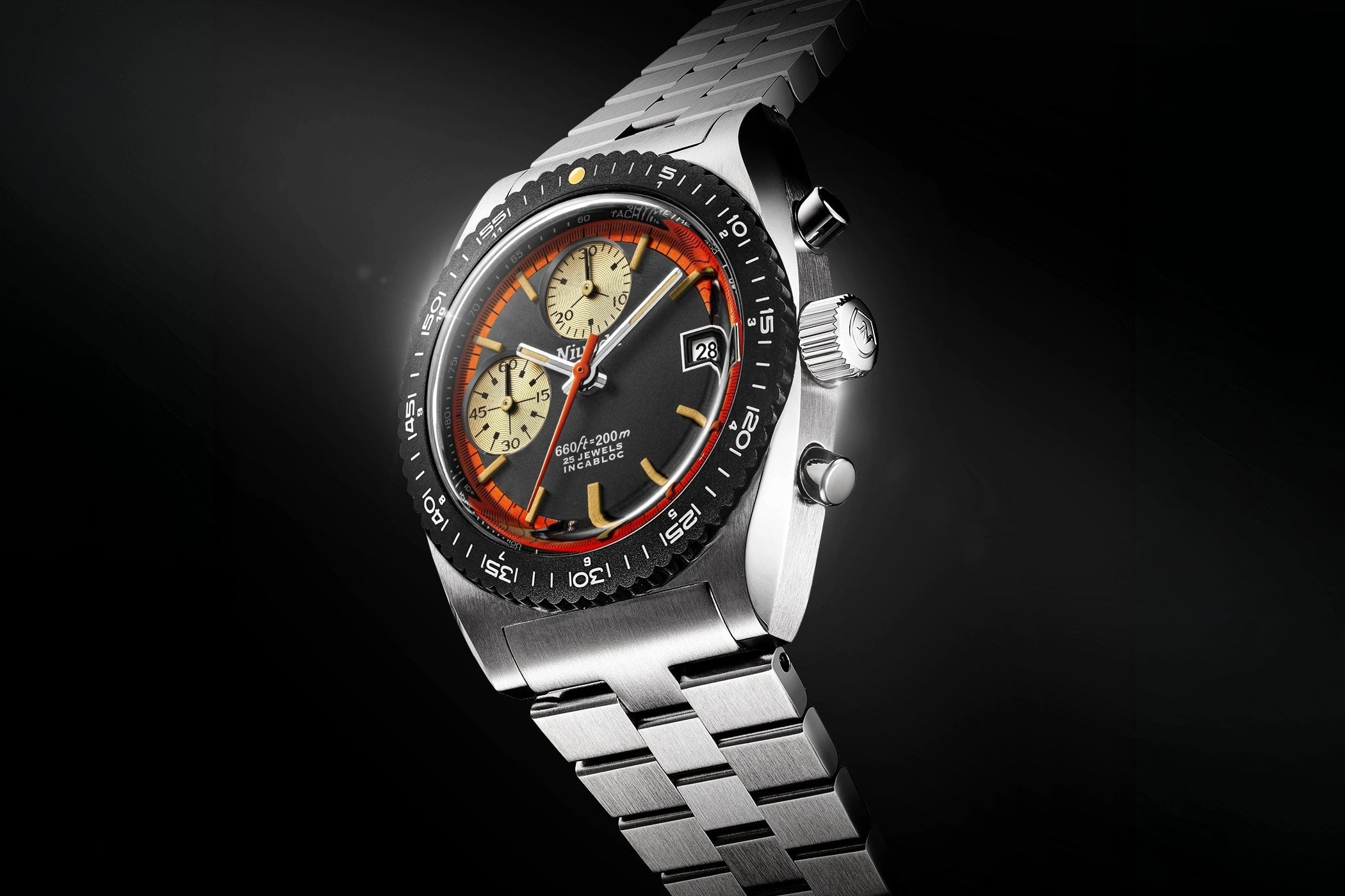 Nivada Grenchen Autochron Automatic Orange at an angle on a steel bracelet, a grained black dial with an orange minute ring, two beige snailed subdials, an orange central chronograph seconds hand and a black-coated rotating bezel