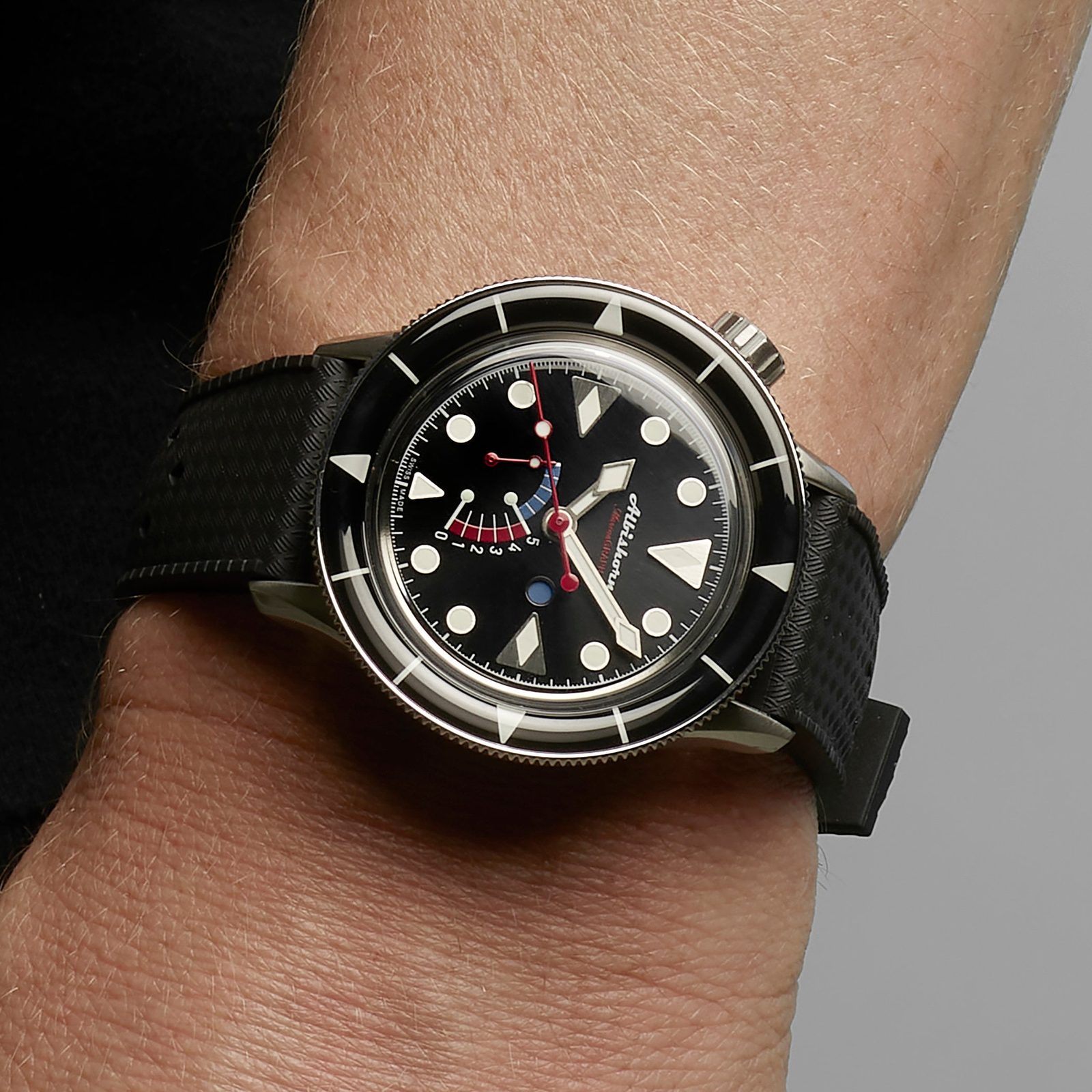 Wrist shot of the black Classic Marinagraph on a black tropic-style rubber strap, the domed sapphire bezel and retrograde countdown scale catching the light