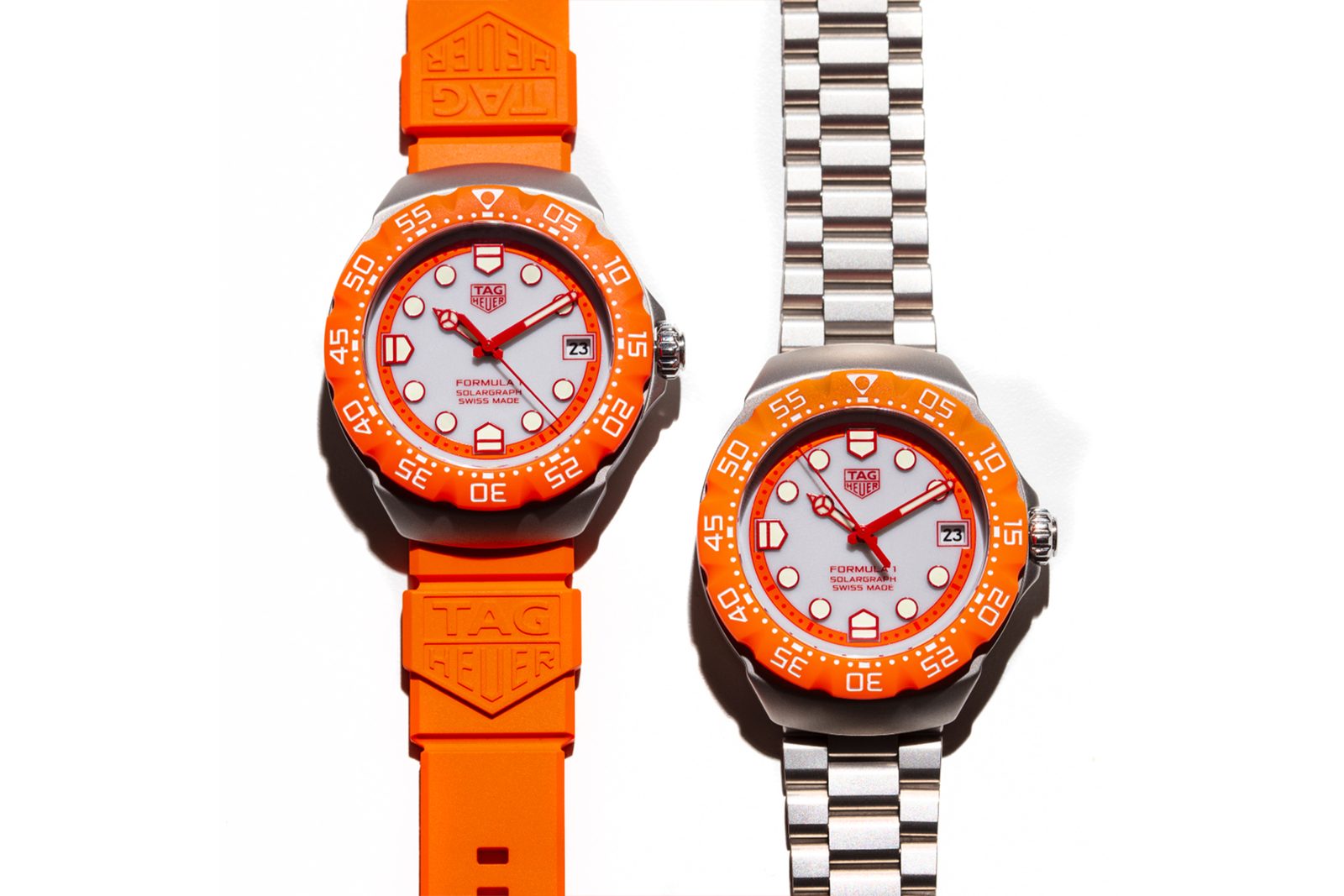 The two Zandvoort editions side by side, reference WBY111H on an orange rubber strap on the left and reference WBY111L on a three-row steel bracelet on the right, both with grey opaline dials and orange bezels