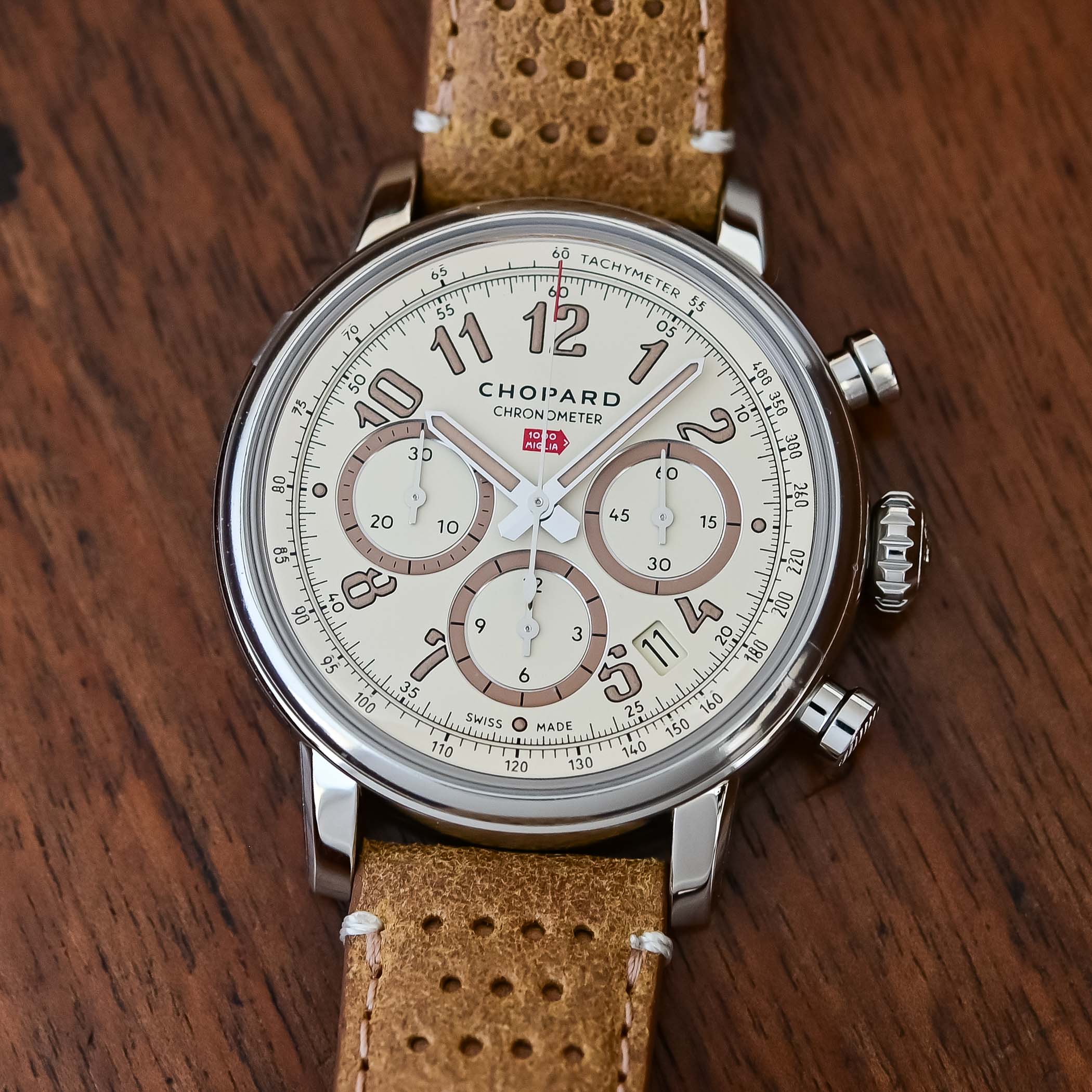 Top-down view of the Chopard Mille Miglia Raticosa's eggshell dial, three taupe-ringed sub-dials in a tri-compax layout, printed tachymeter scale, date between four and five o'clock and the red 1000 Miglia arrow below CHOPARD CHRONOMETER