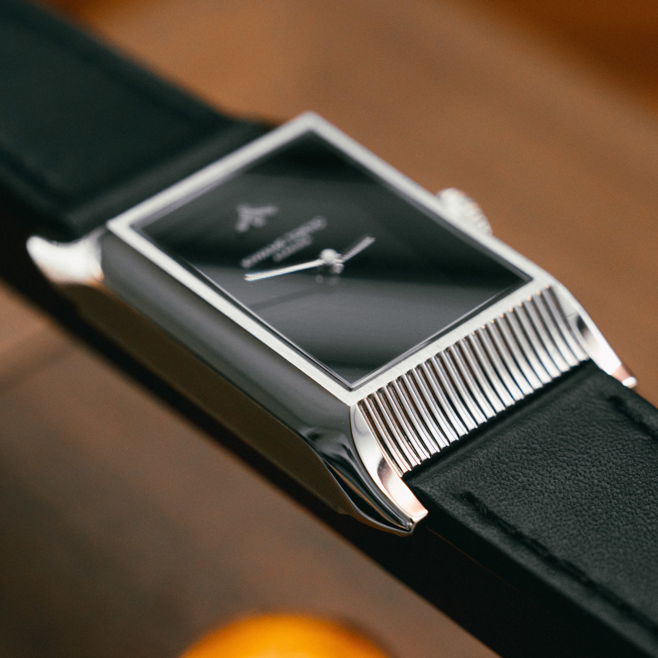 Close-up of the Yane's polished steel case flank and grooved end, the reeded rows standing in for temple roof tiles beside the black lacquer dial reading KIWAME TOKYO ASAKUSA