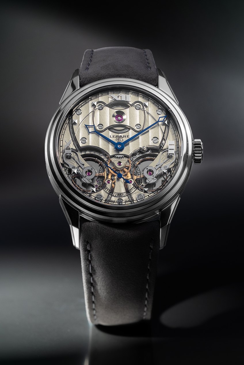 Three-quarter view of the Legaré Chapter I in Grade 5 titanium at 37.5mm, showing the case flank and lugs, the striped German-silver dial and the openworked movement beneath, on a grey suede strap