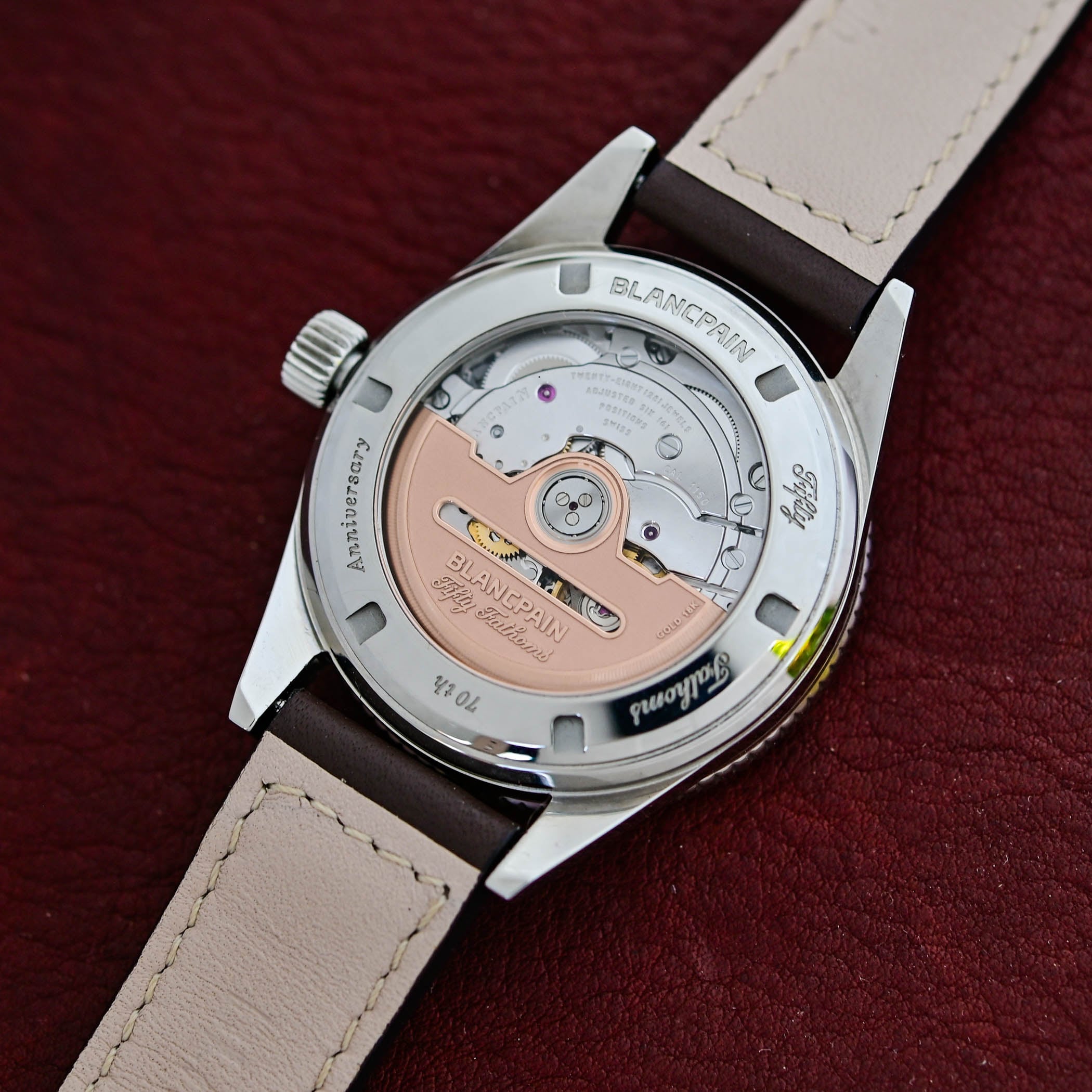 The sapphire caseback revealing the Blancpain Calibre 1150, its openworked 18K gold rotor engraved Blancpain Fifty Fathoms and Gold 18K, with the anniversary engraving around the bezel of the steel back