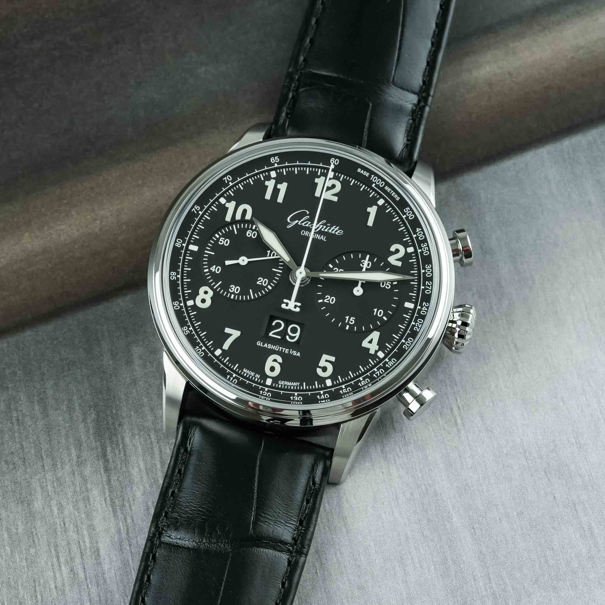 The Senator Chronograph Navigator, the sibling model, with a matte black lacquer dial, solid luminous Arabic numerals, white lacquer chronograph hands and registers and the Panorama Date at six, on a black alligator strap