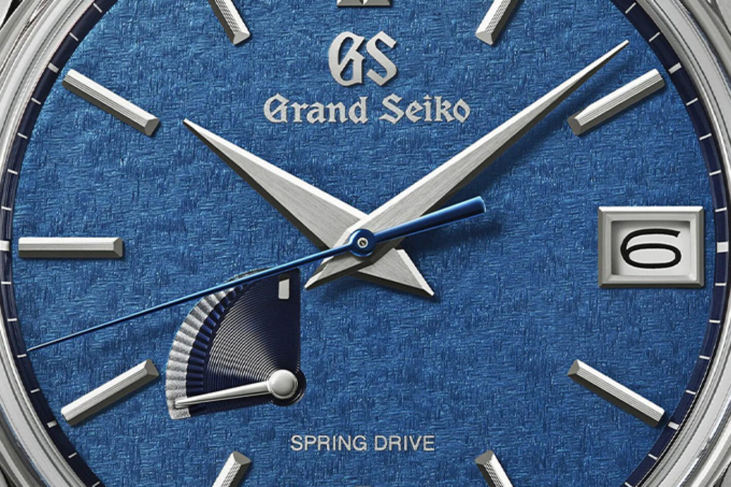 A macro of the SBGA527 dial showing the textured deep-blue surface, the Grand Seiko logo, faceted diamond-cut markers, the blued Spring Drive seconds hand and the fan-shaped power reserve indicator at eight