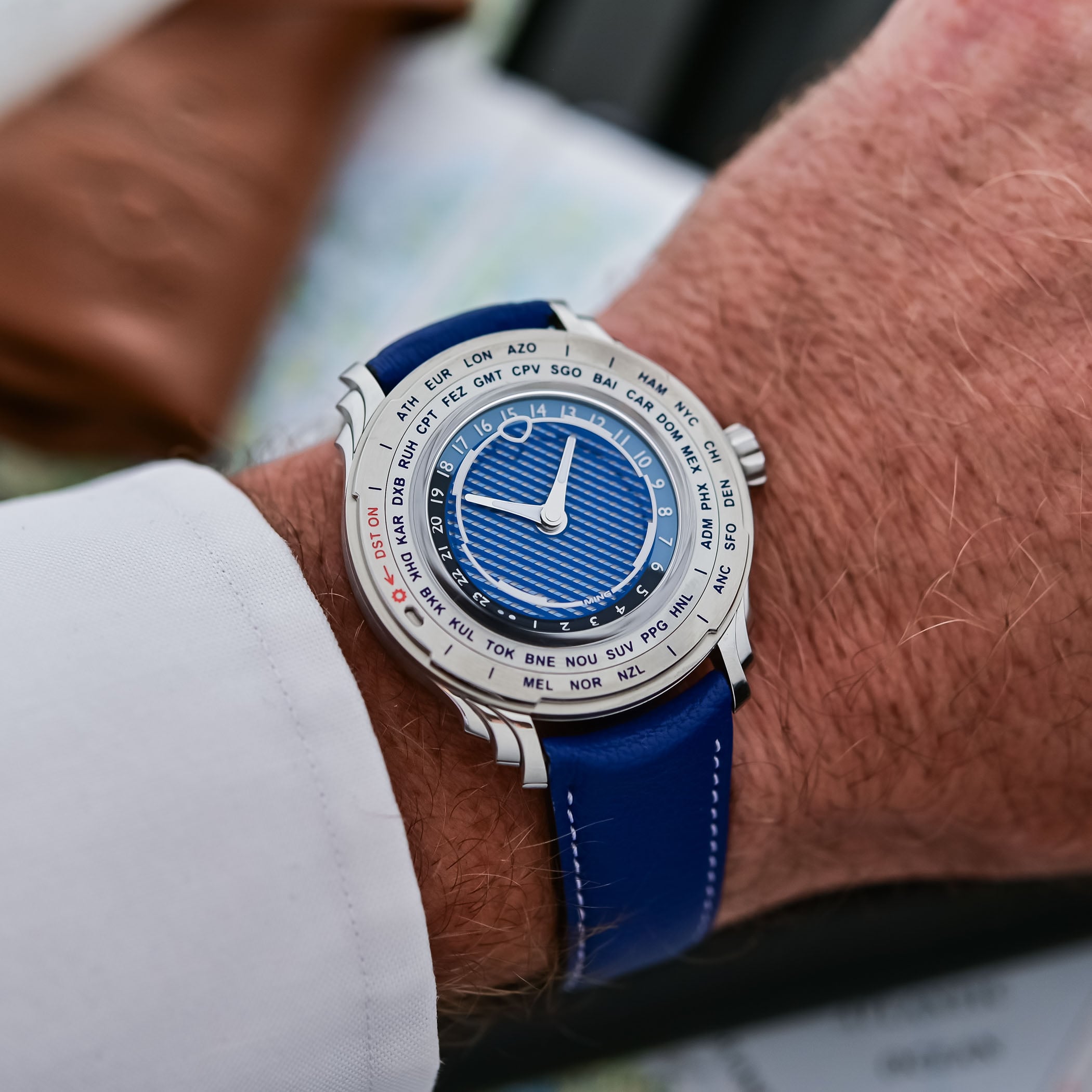 The Ming 57.05 Comet worn on the wrist on its cobalt-blue leather strap, the 40mm steel case and blue worldtime dial in daylight
