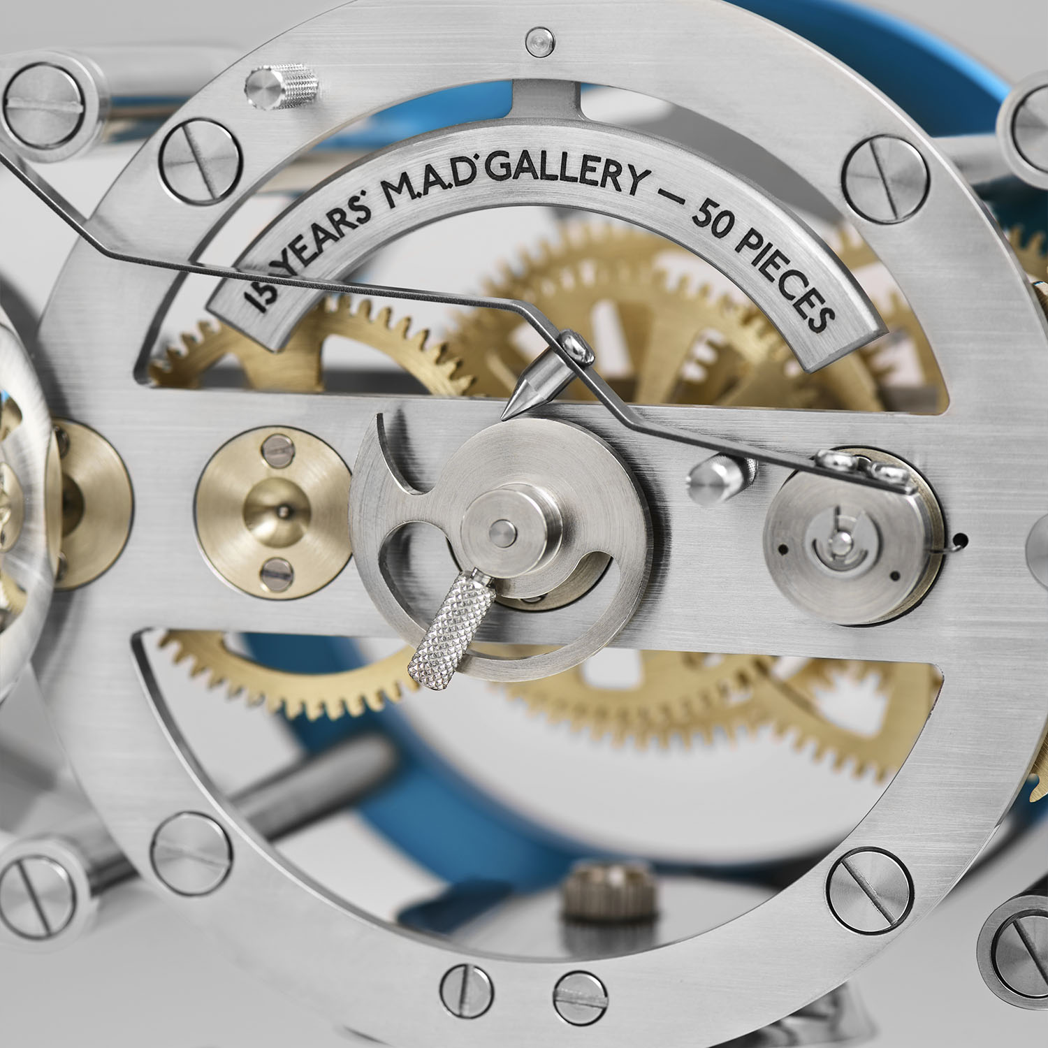 A macro of the Nostromo movement, the balance and an engraved arc reading 15 Years M.A.D.Gallery and 50 Pieces above the brass going train