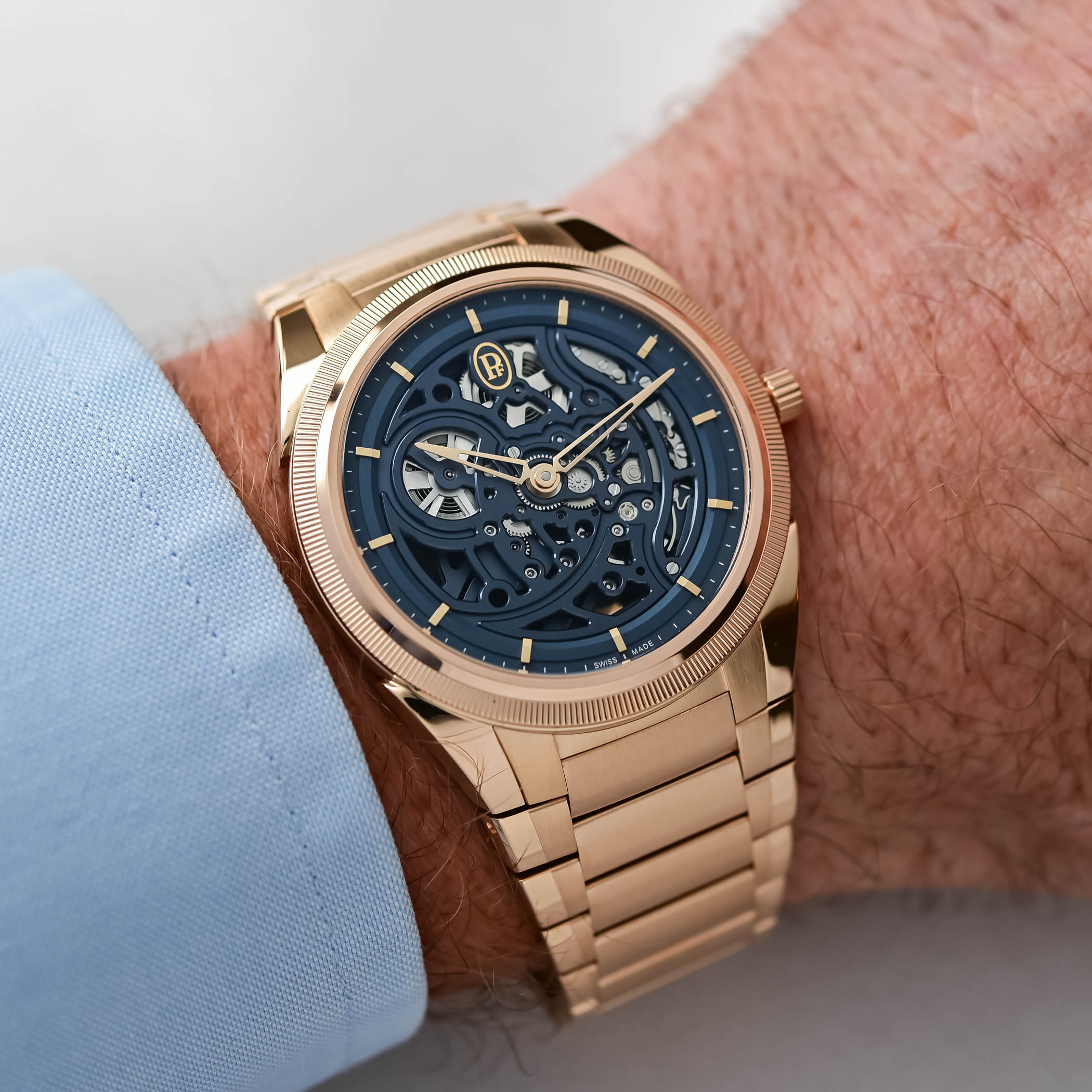The Parmigiani Tonda PF Skeleton Rose Gold Milano Blue on the wrist below a light blue shirt cuff, rose gold case and integrated bracelet with the deep blue skeleton dial