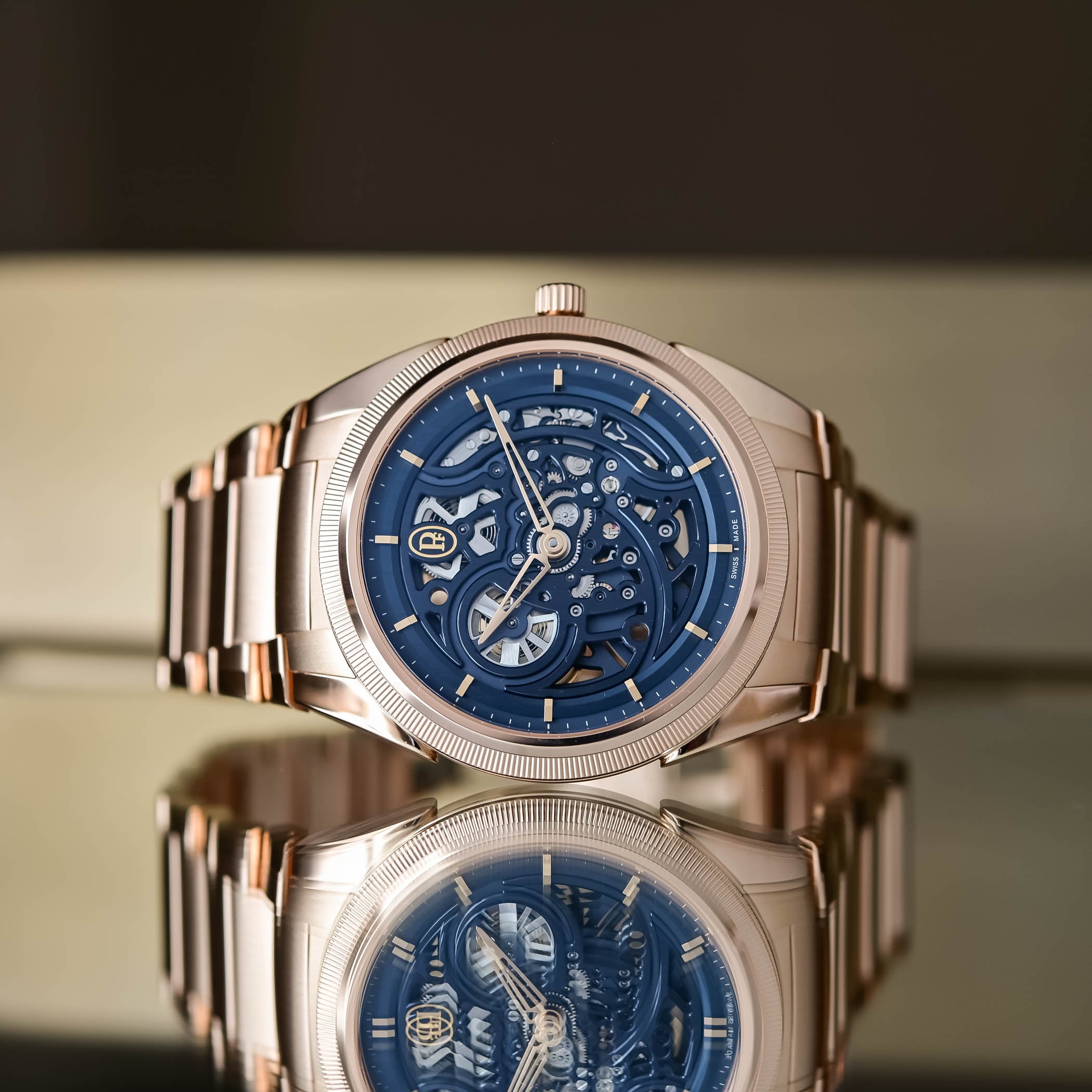 A straight-on view of the Tonda PF Skeleton Rose Gold Milano Blue standing on a reflective surface, showing the knurled rose gold bezel and the blue openworked dial