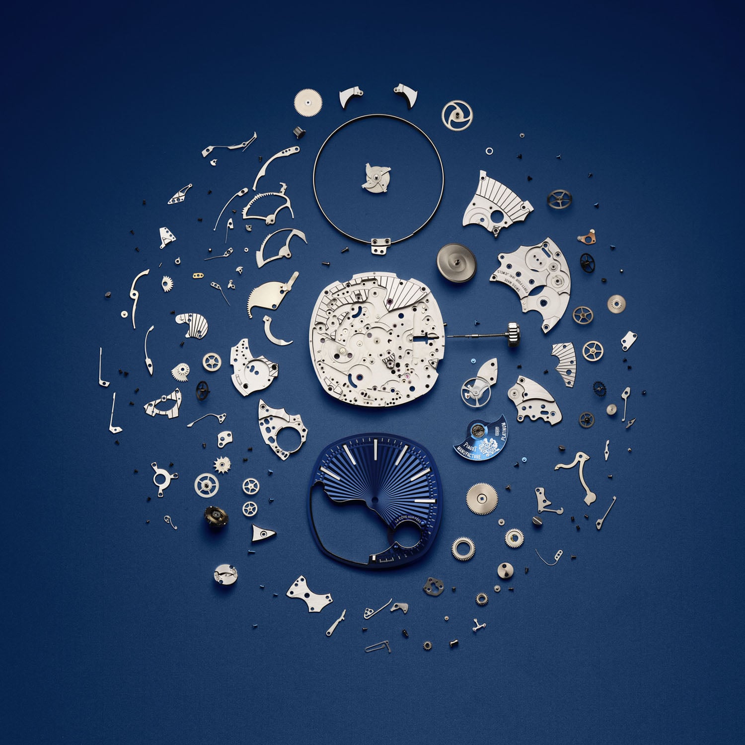 The 430 components of the Piaget calibre 1290P laid out on a blue ground around the openworked main plate and the blue guilloche dial