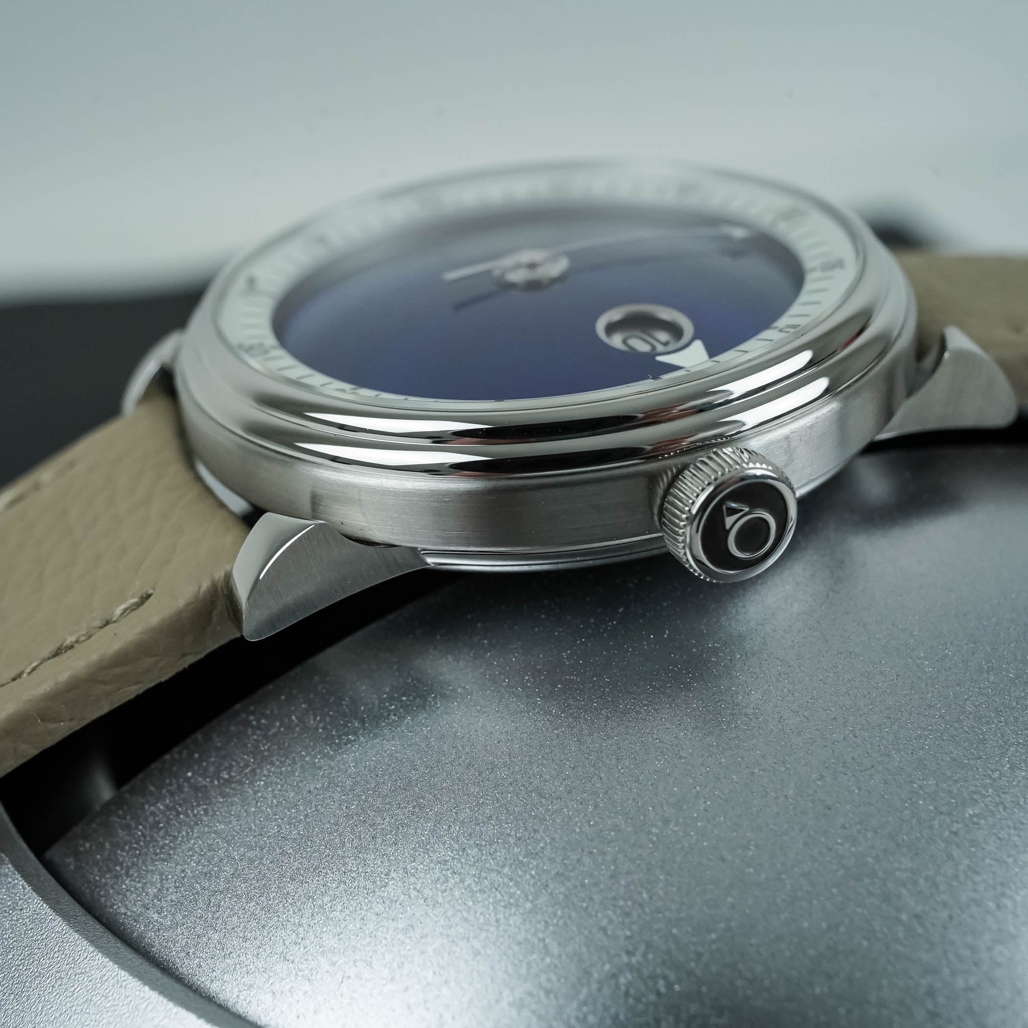 The M.A.D.3 in side profile, the brushed and polished steel case with floating lugs, a double-step bezel and a domed sapphire crystal, on a beige leather strap