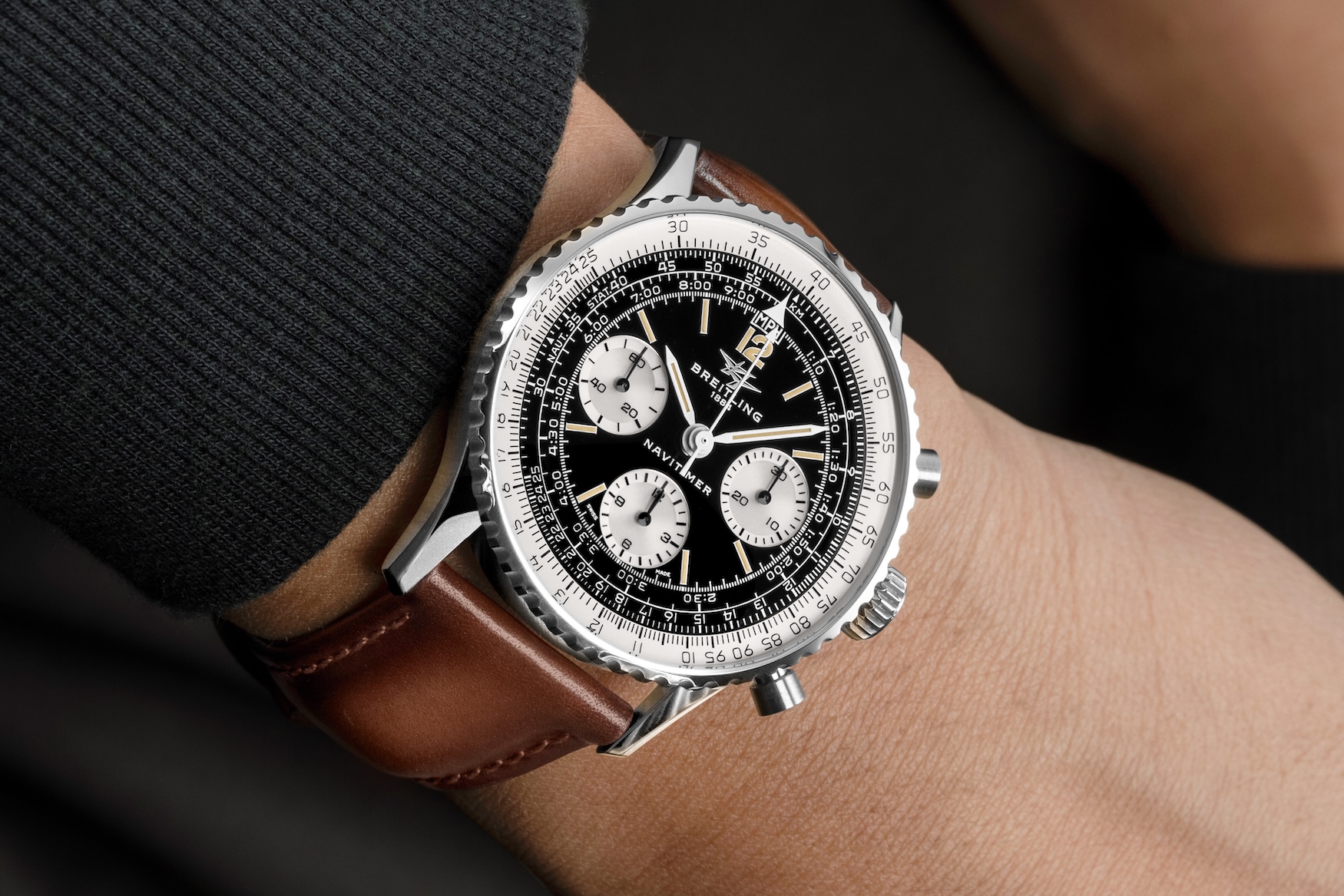 A wrist shot of the steel Navitimer B09 Miles Davis on a brown leather strap, showing the black reverse-panda dial, the Twin-Jet logo, the slide-rule bezel and the MPH scale