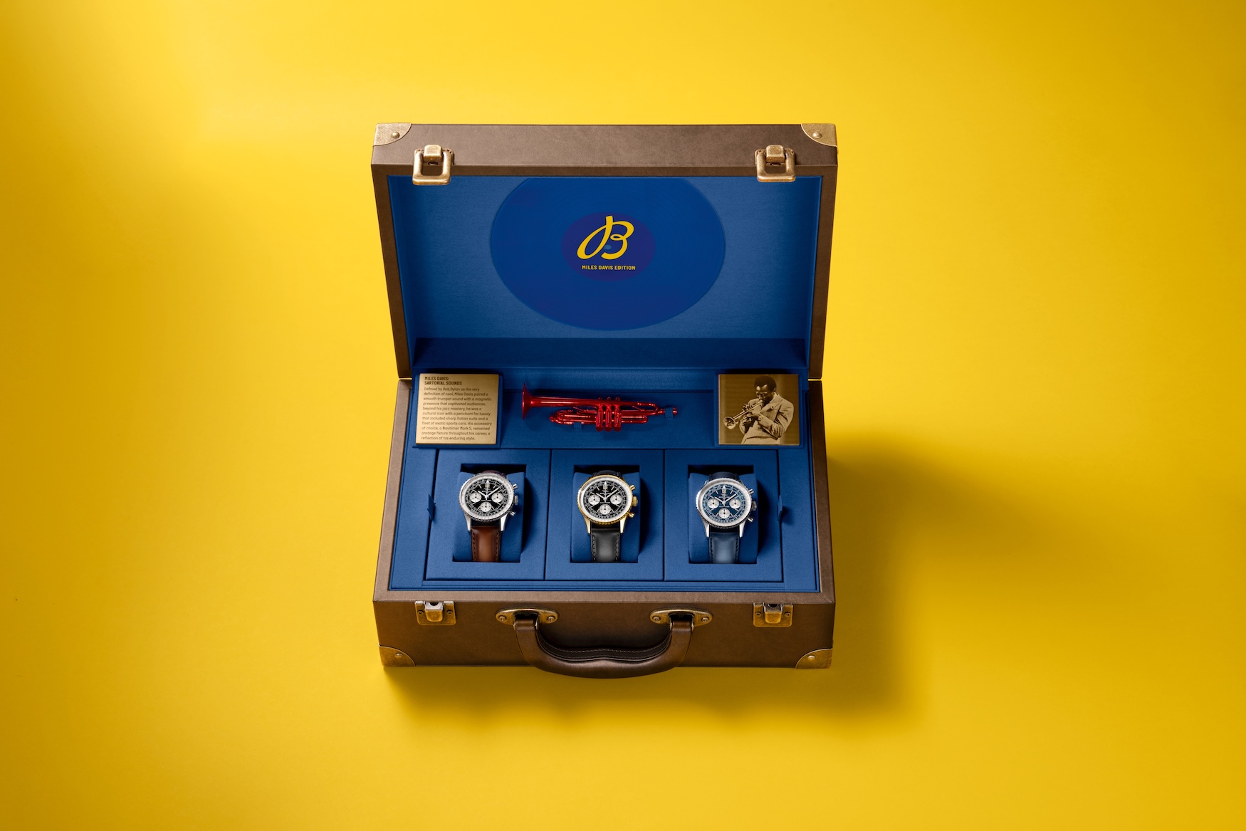 The Miles Davis Edition presentation case with a red trumpet and a photo of Davis, holding the three versions of the tribute, steel on brown leather, yellow gold on black leather and platinum on a blue strap