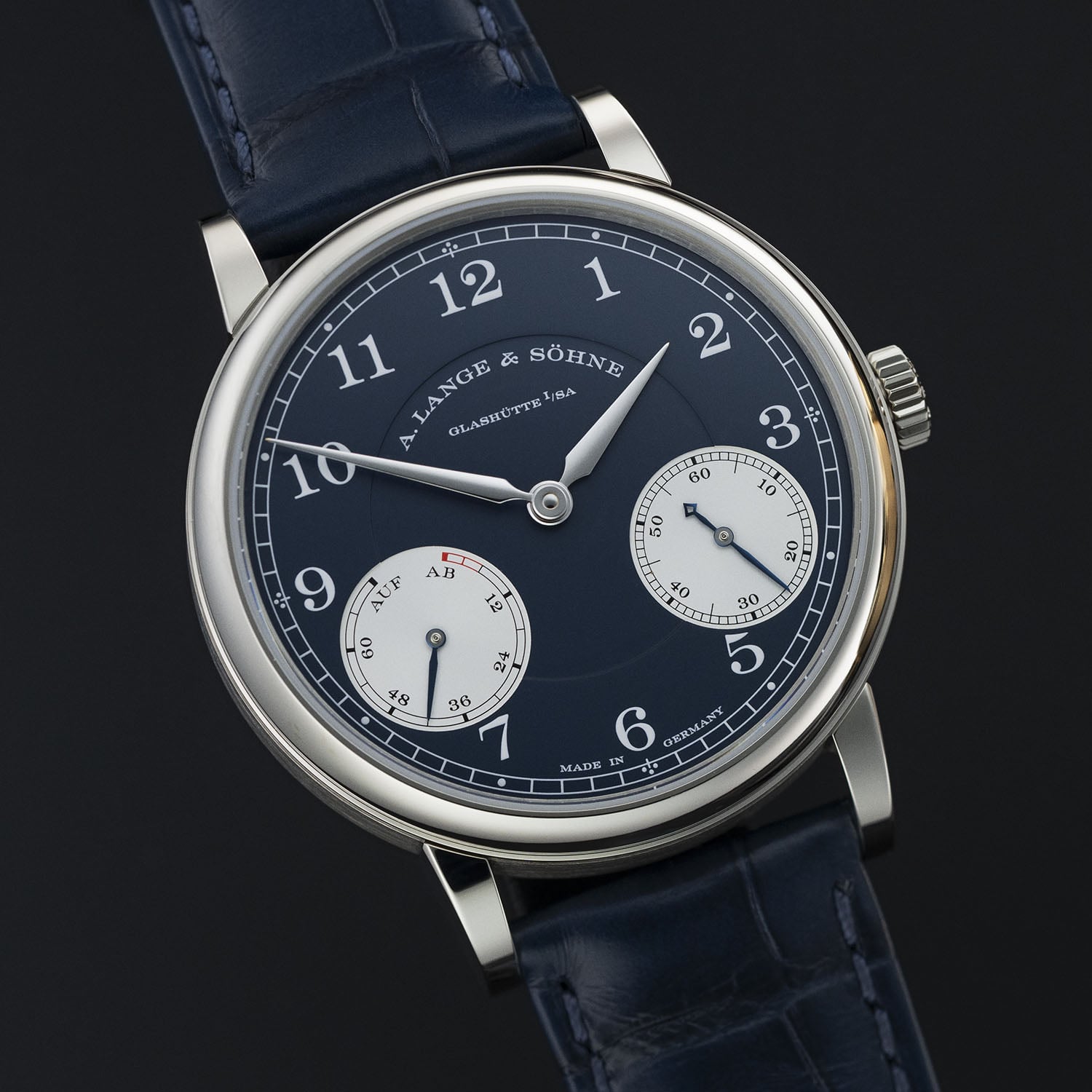 The white gold A. Lange & Söhne 1815 Up/Down at an angle, blue dial with the AUF/AB power-reserve sub-dial at eight o'clock showing its red depleted-power segment and the snailed small-seconds counter at four, on a blue alligator strap