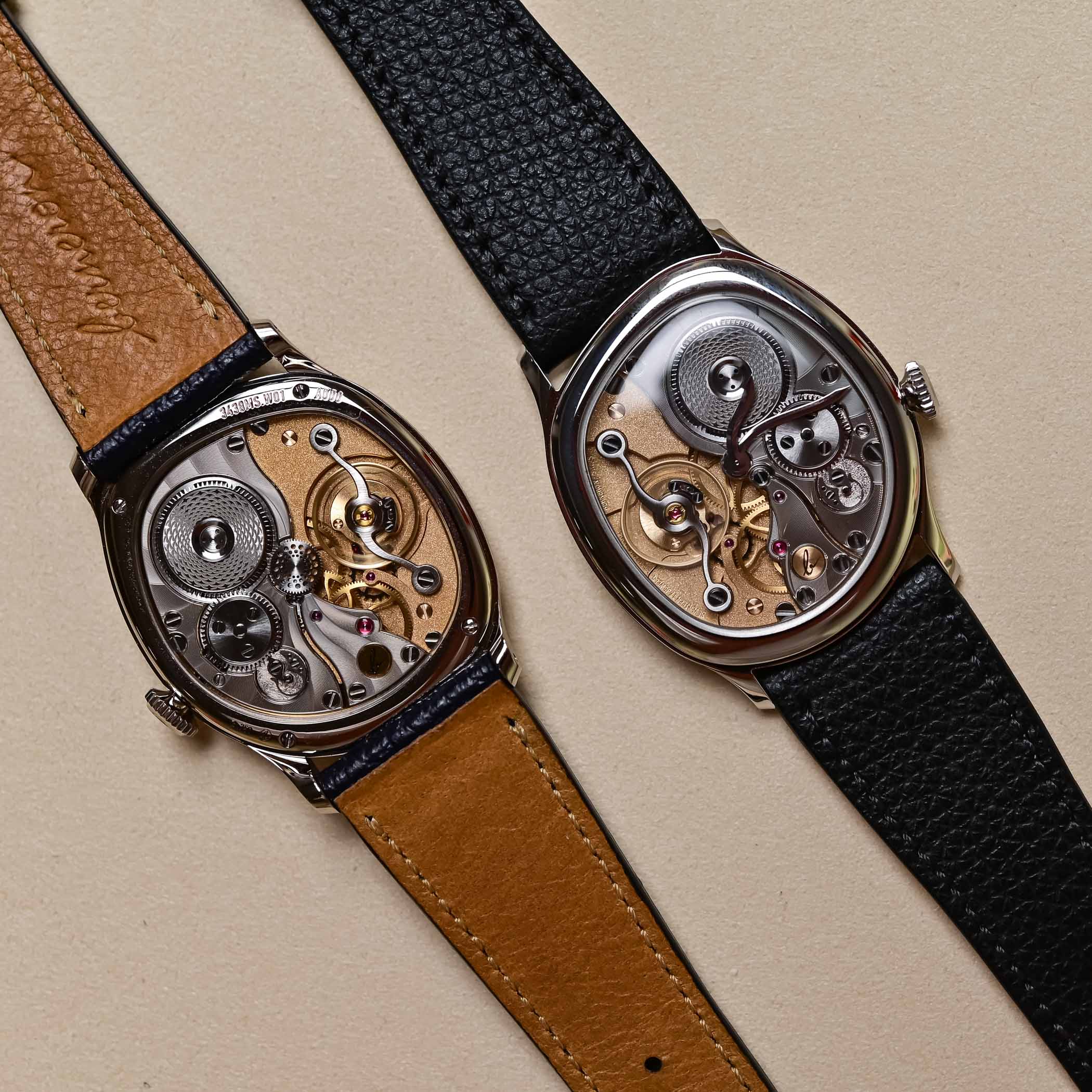 The new Berneron Mirage 38 Miroir on the right beside the movement side of the original Mirage on the left, both in gold cushion cases laid on a beige ground, showing how the Miroir mirrors the earlier construction