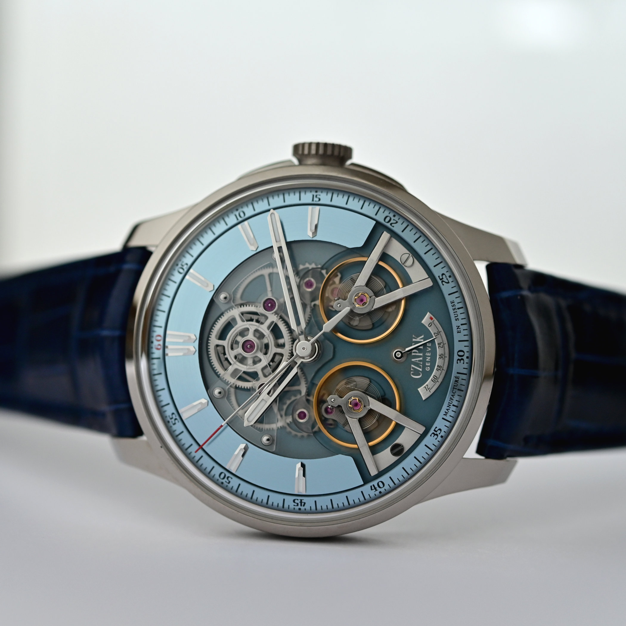 A low three-quarter view showing the domed sapphire crystal, the sandblasted hollowed-out lugs of the platinum case and the exposed twin-balance movement