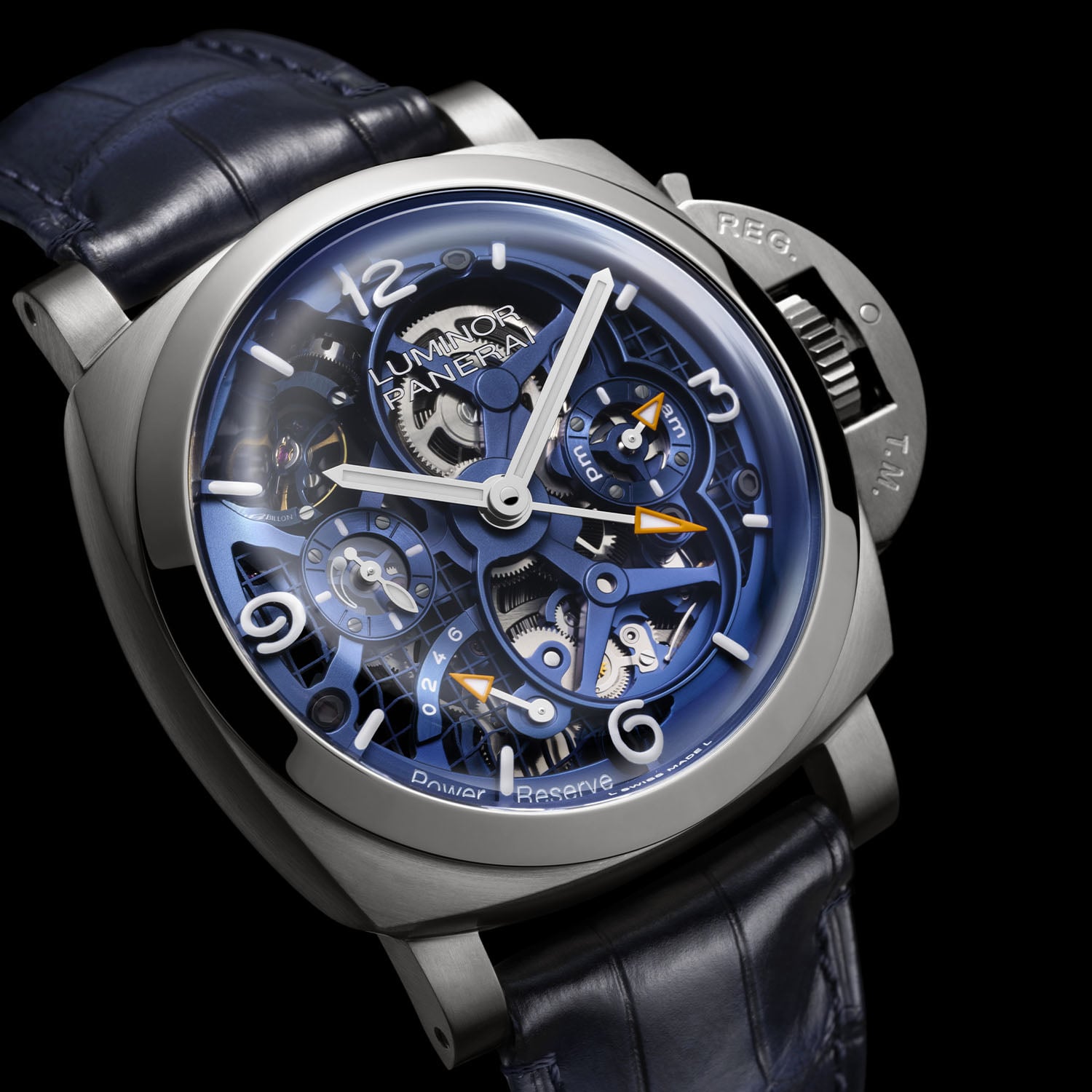 A three-quarter view of the Panerai PAM01784 in brushed titanium on a black ground, showing the crown-protecting bridge, the blue skeletonised dial and the AM/PM sub-dial